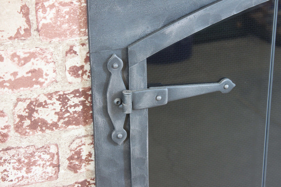 Close-up of the textured frame and strap hinge on Forged Iron fireplace doors