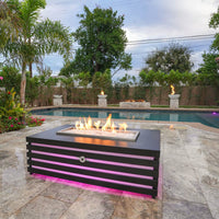 Amina Rectangle Powder Coat Steel fire pit table on a patio with flames burning