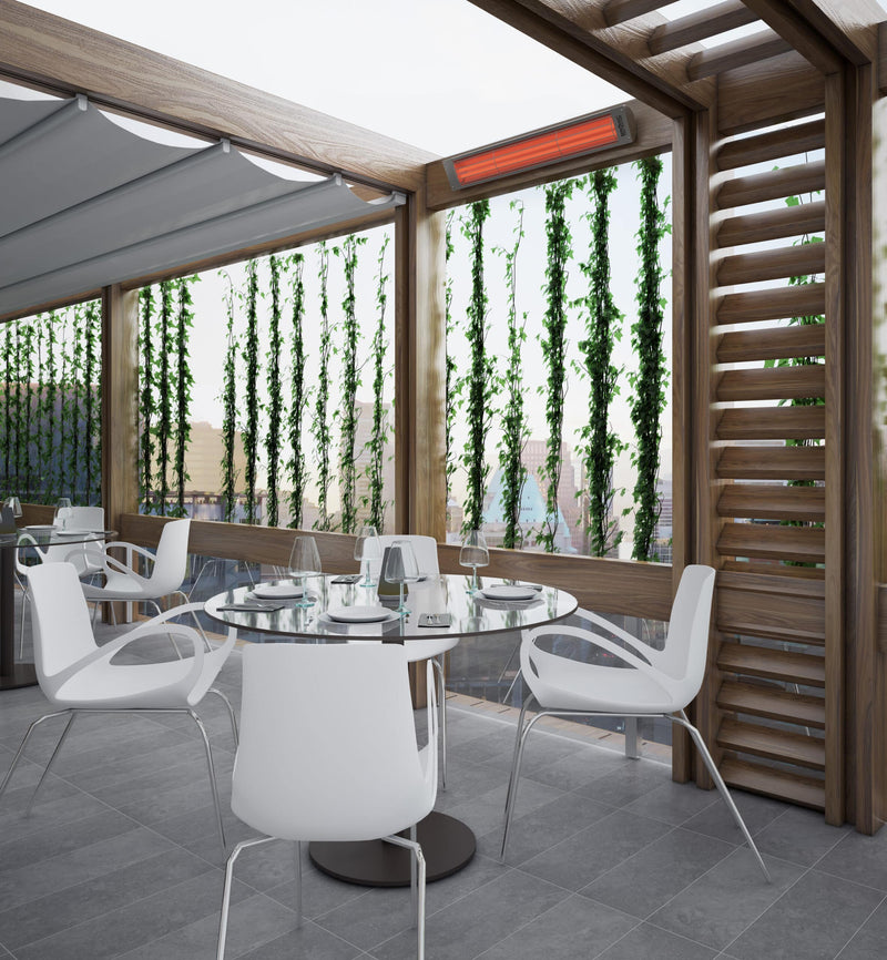 Bromic Cobalt Electric heater mounted above a wood-framed restaurant terrace with dining tables. Manufacturer installation inspiration; accessories shown sold separately.