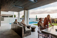 Bromic Tungsten Electric heaters recessed into a wood ceiling above a poolside outdoor dining and seating area. Manufacturer installation inspiration; accessories shown sold separately.