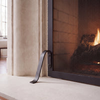 Curved support foot and mounting screws on the limestone hearth — close-up