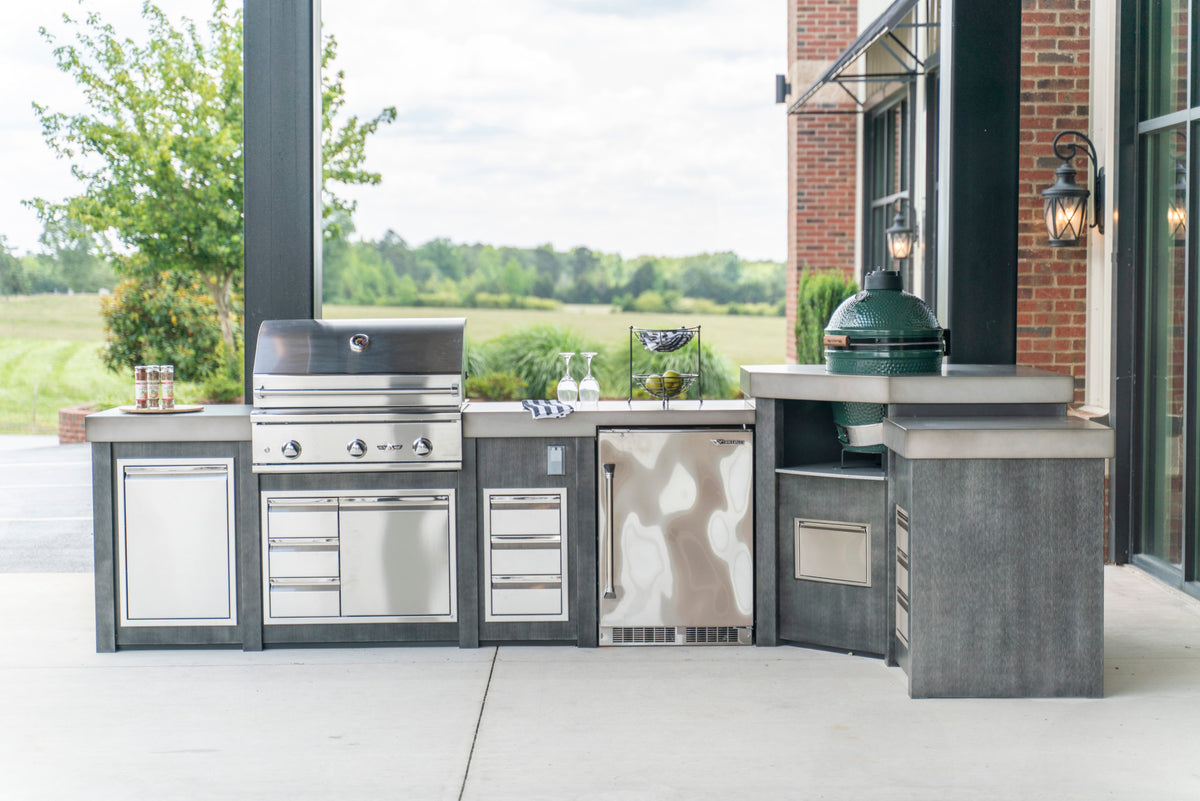Outdoor kitchen with a stainless gas grill, ceramic kamado and storage on a covered patio