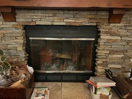 Factory-built firebox: a black metal box set into a stone surround, with louver bands above and below the opening.